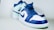 A pair of stylish sneakers featuring a blue and white color scheme. The shoes have a high-top design with blue laces and a prominent brand logo on the side panel. The background is a simple, neutral tone, highlighting the vivid colors of the sneakers.