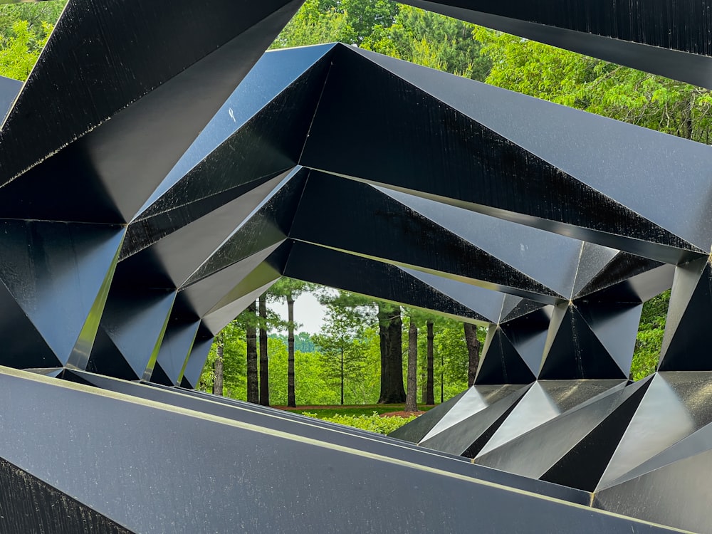 a large metal structure with trees in the background