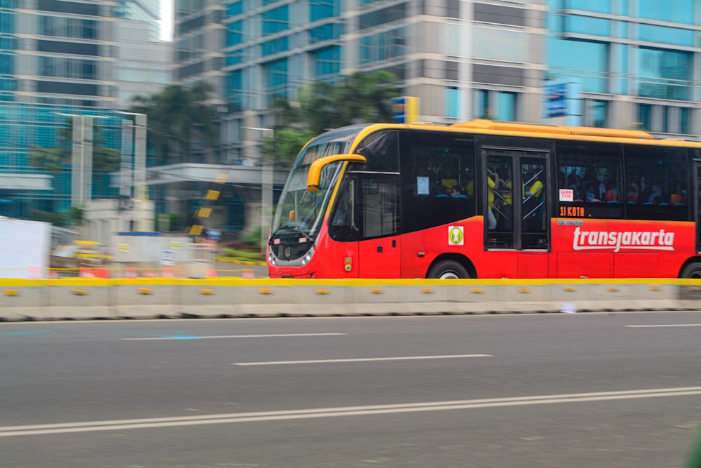 a red bus driving down a street next to tall buildings