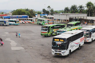 A fleet of comfortable buses parked at Nafira Trans terminal in Indramayu during sunset.
