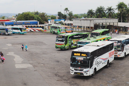 A fleet of comfortable buses parked at Nafira Trans terminal in Indramayu during sunset.