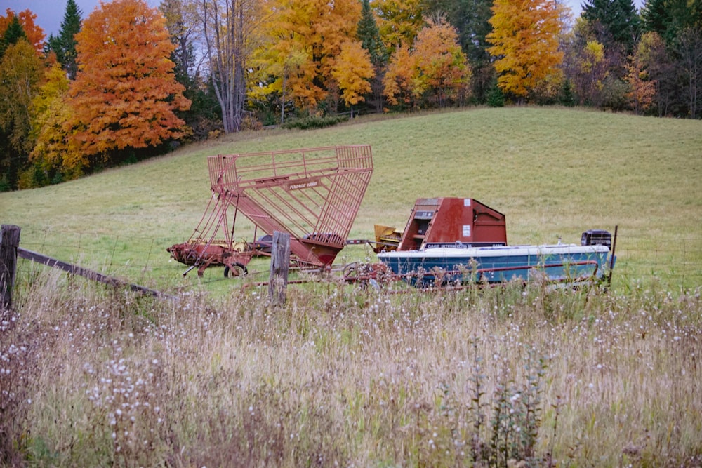 a rusted out boat sitting in a field next to a fence