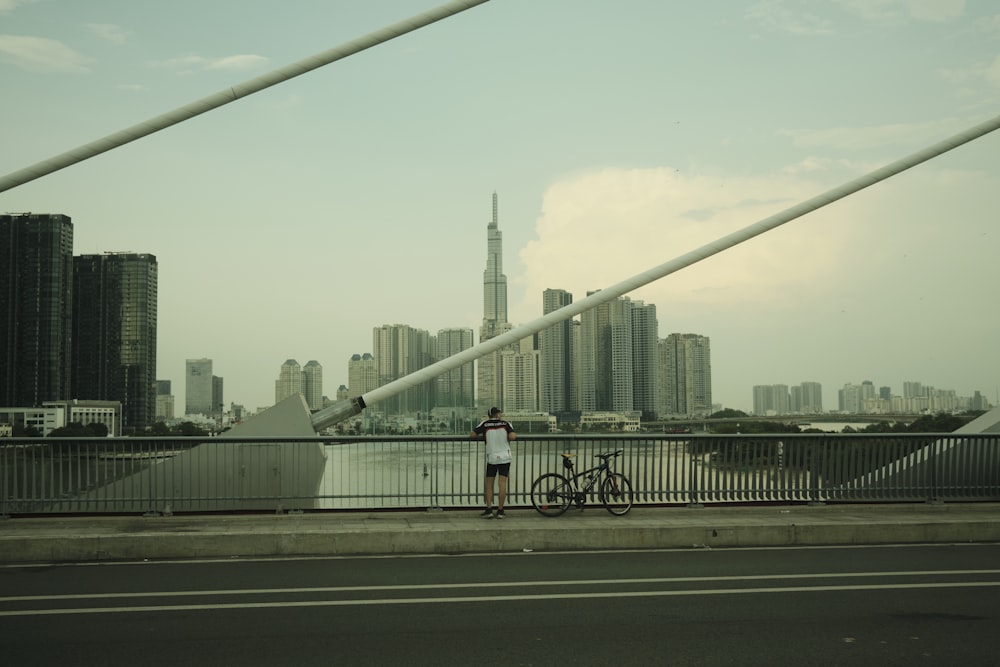 a person standing next to a bike on a bridge