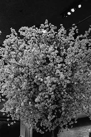 A panoramic view of Florévo’s bustling factory floor with skilled artisans assembling hyper-realistic floral arrangements under bright, clean lighting.