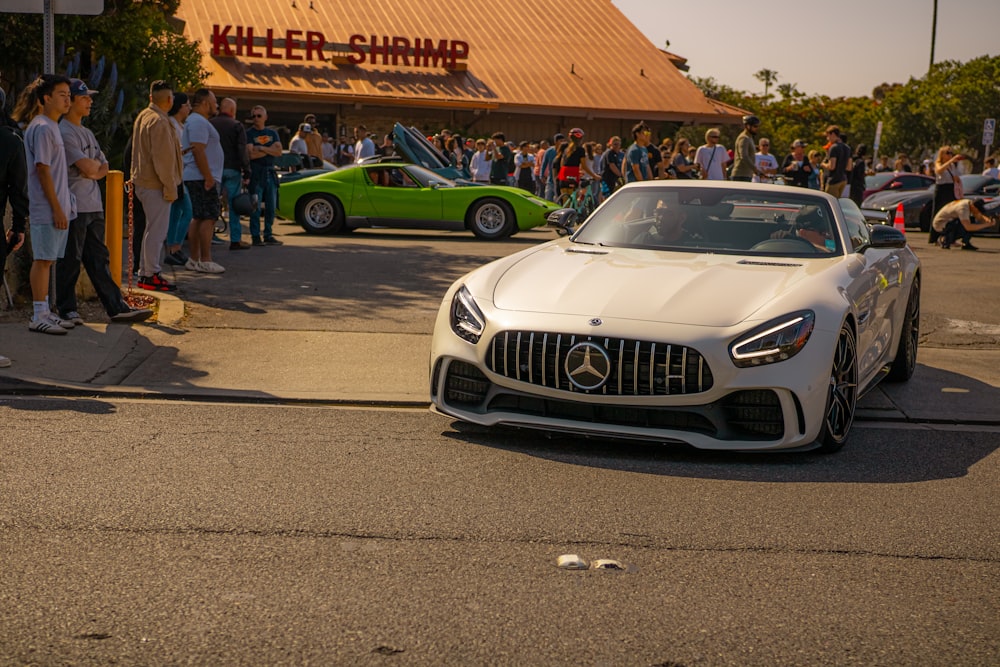 a mercedes sports car parked in front of a crowd of people