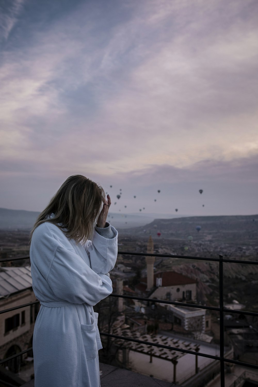 a woman in a bathrobe standing on a balcony