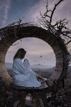 a woman in a white robe sitting on a wooden bench