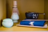 A serene scene of a Japanese tea cup next to a jar of moisturizing cream on a bamboo mat.