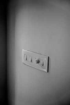 A stylish dimmer switch with a smooth rotary knob glowing warmly against a neutral wall.