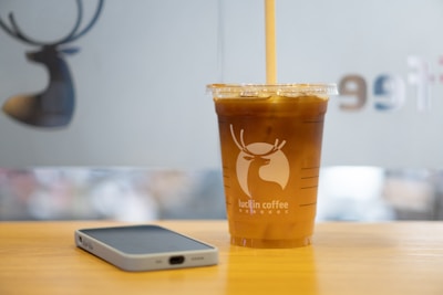 A photo showing the sharp detail of a printed logo on a clear plastic cup filled with iced coffee.