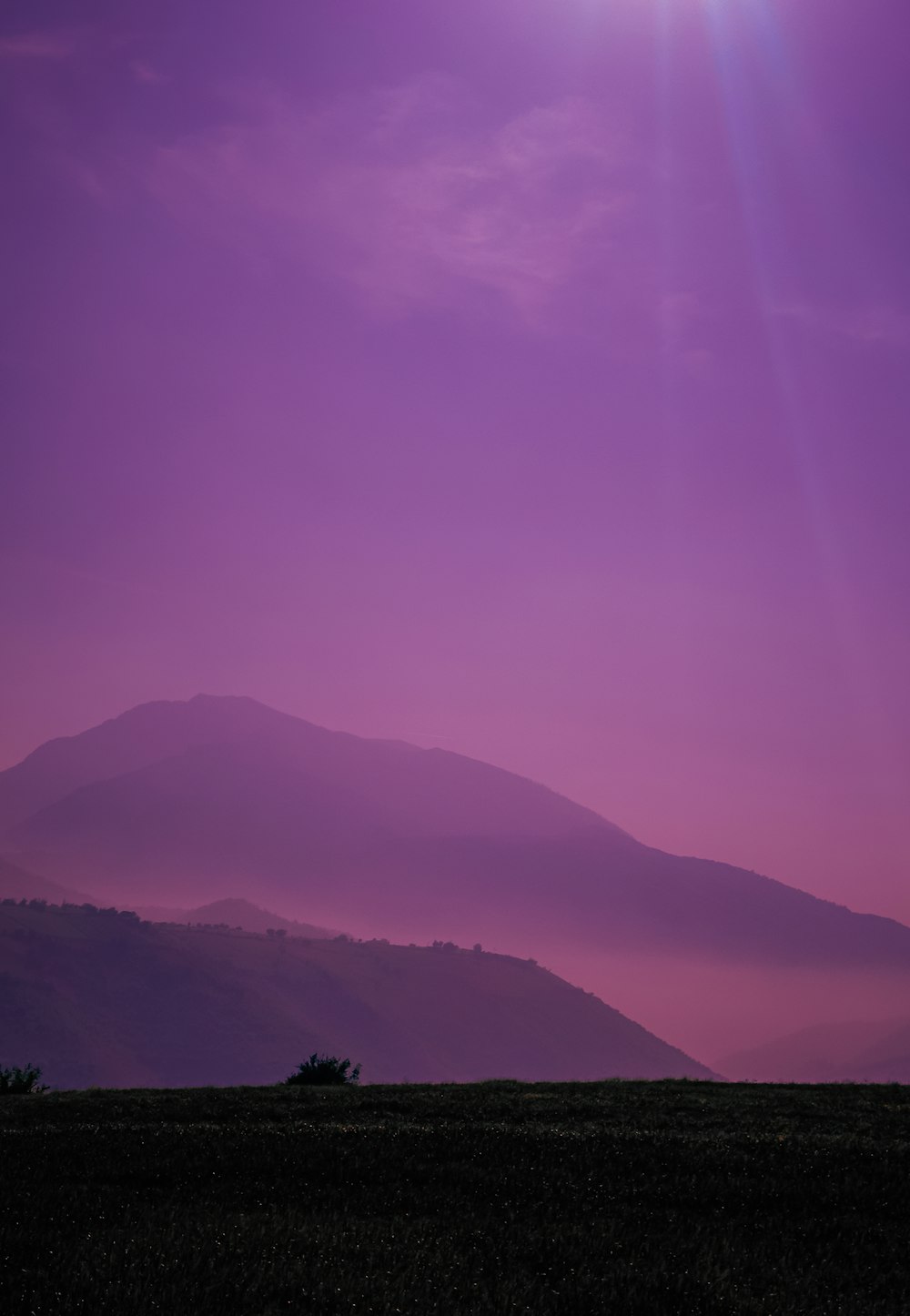 the sun is setting over a mountain range