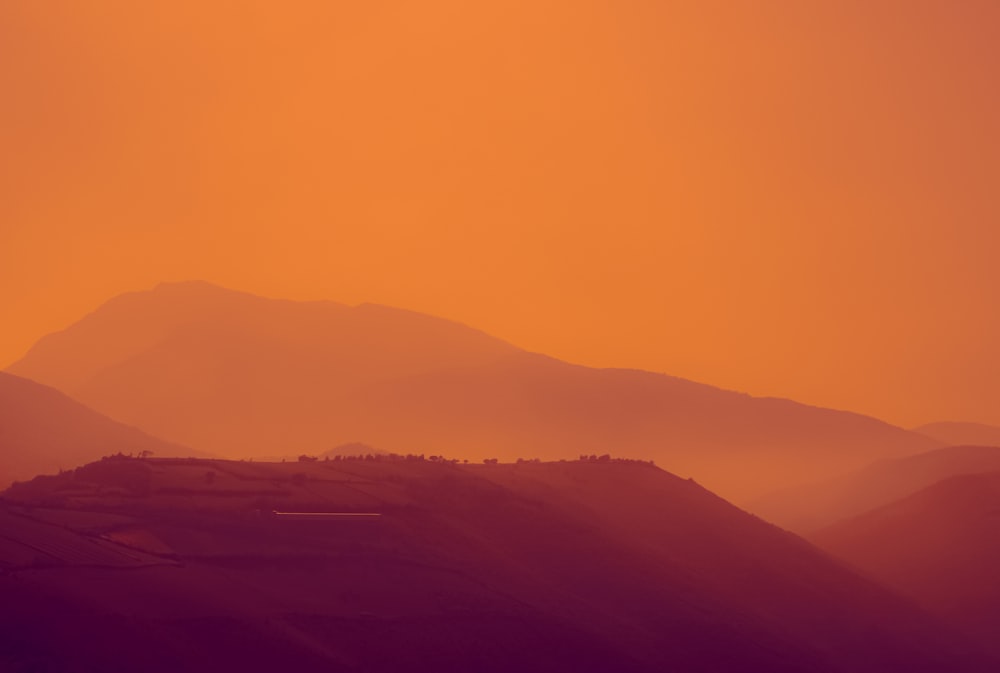 a plane flying over a mountain range at sunset