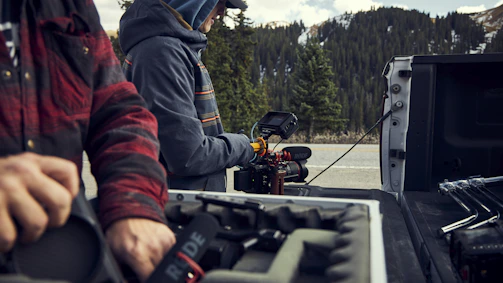 Film crew setting up camera equipment on a mountain location.