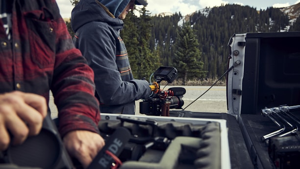 Technicians setting up audio and video equipment in a rustic outdoor setting at sunset.