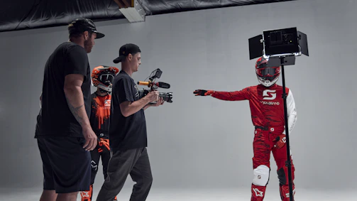 Behind-the-scenes shot of a creative team planning a motorcycle gear photoshoot in a minimalist studio.