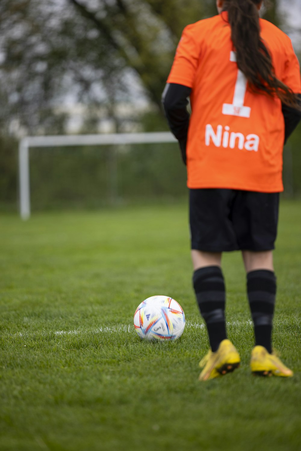 a soccer player in an orange jersey is about to kick a soccer ball