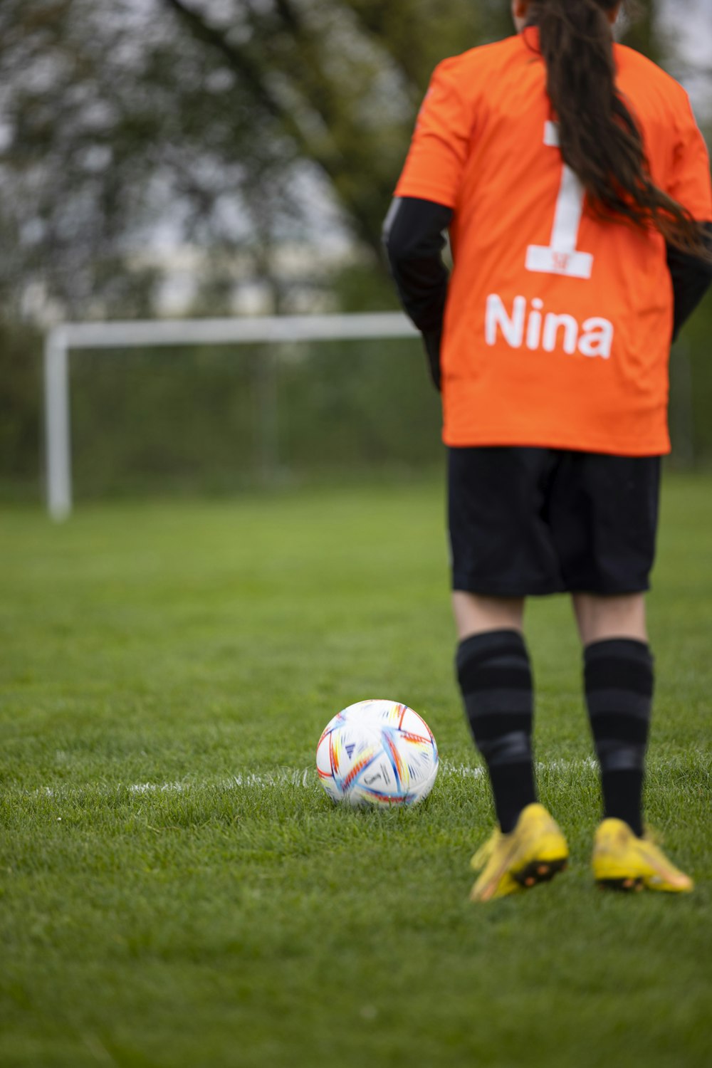 Un calciatore in maglia arancione sta per calciare un pallone da calcio