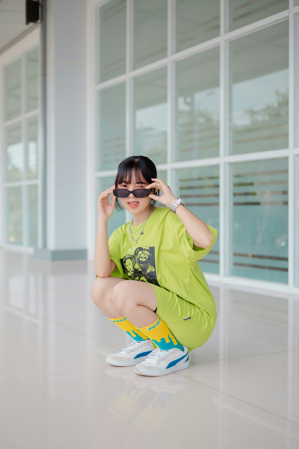 a woman sitting on the ground wearing a pair of sunglasses