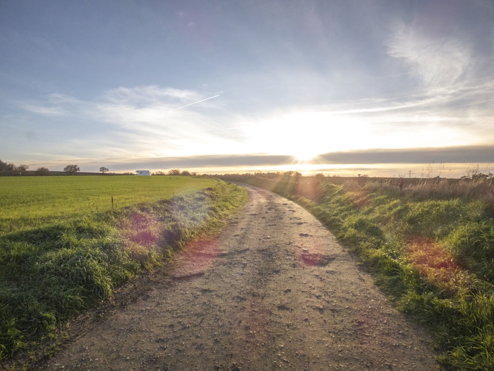 a dirt road with a field in the background