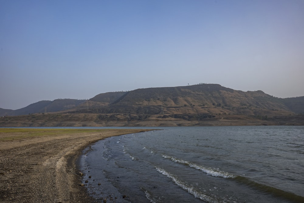 a body of water with a hill in the background