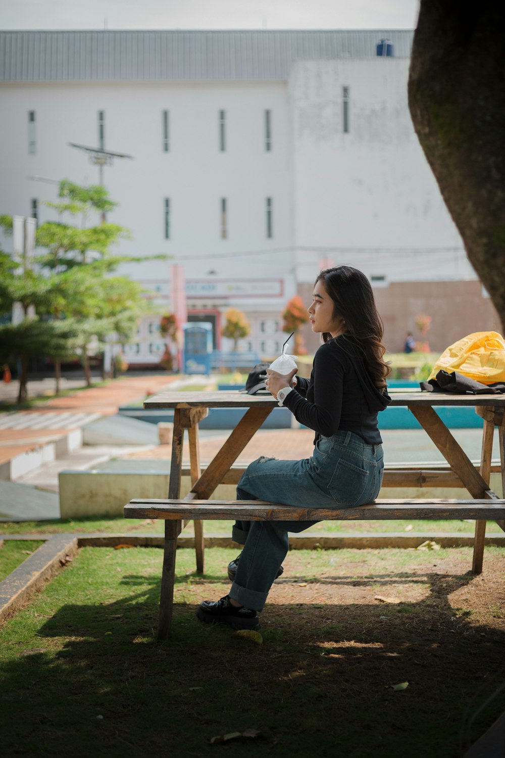 a woman sitting on a bench drinking from a cup