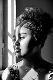 A confident woman wearing a voluminous, curly wig styled to perfection in natural light.