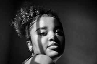 A serene black-and-white portrait highlighting natural light and subtle shadows.