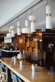 a restaurant with wooden tables and chairs and hanging lights