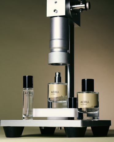 three bottles of perfume sitting next to a machine