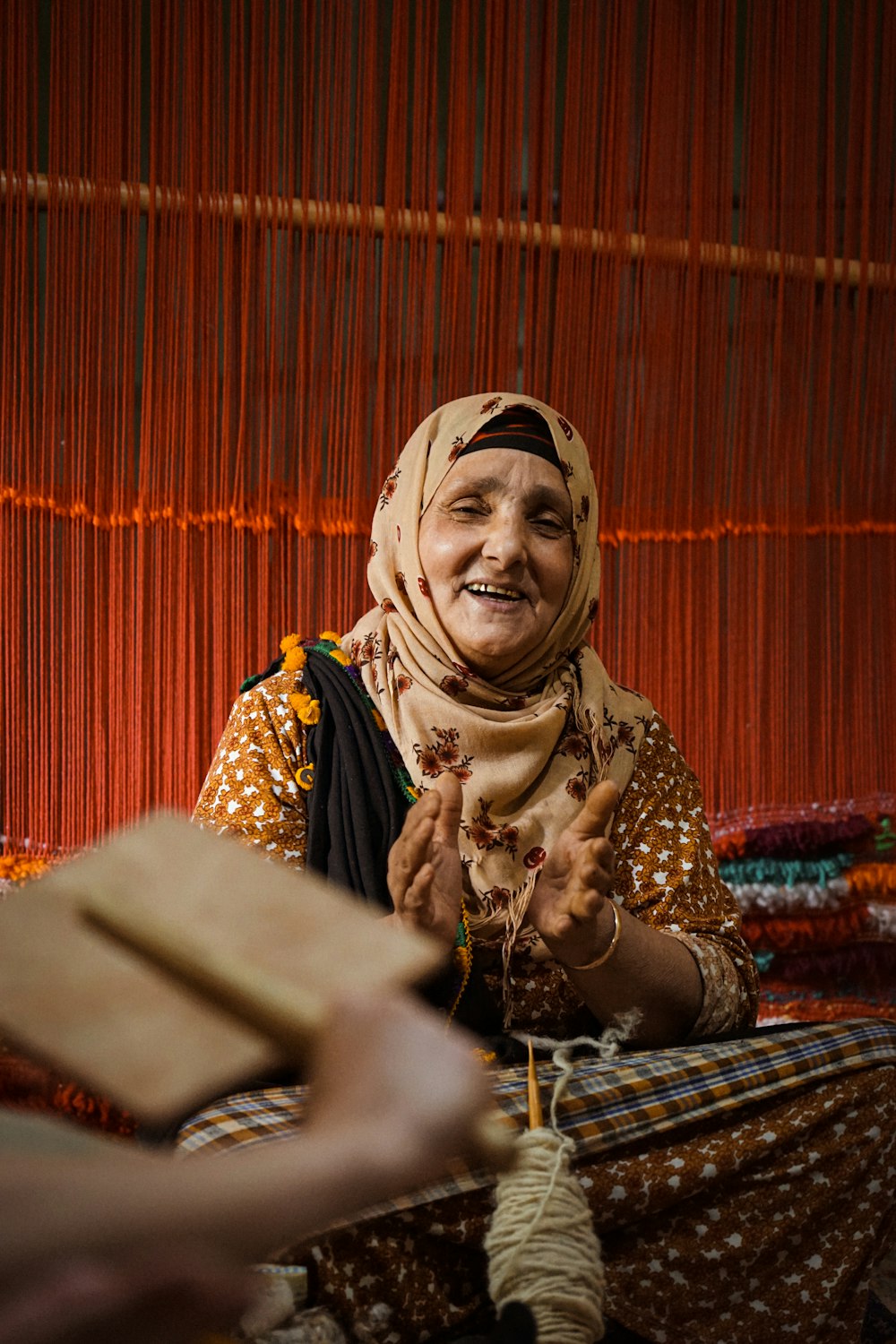 Une femme portant un foulard sourit assise sur un lit