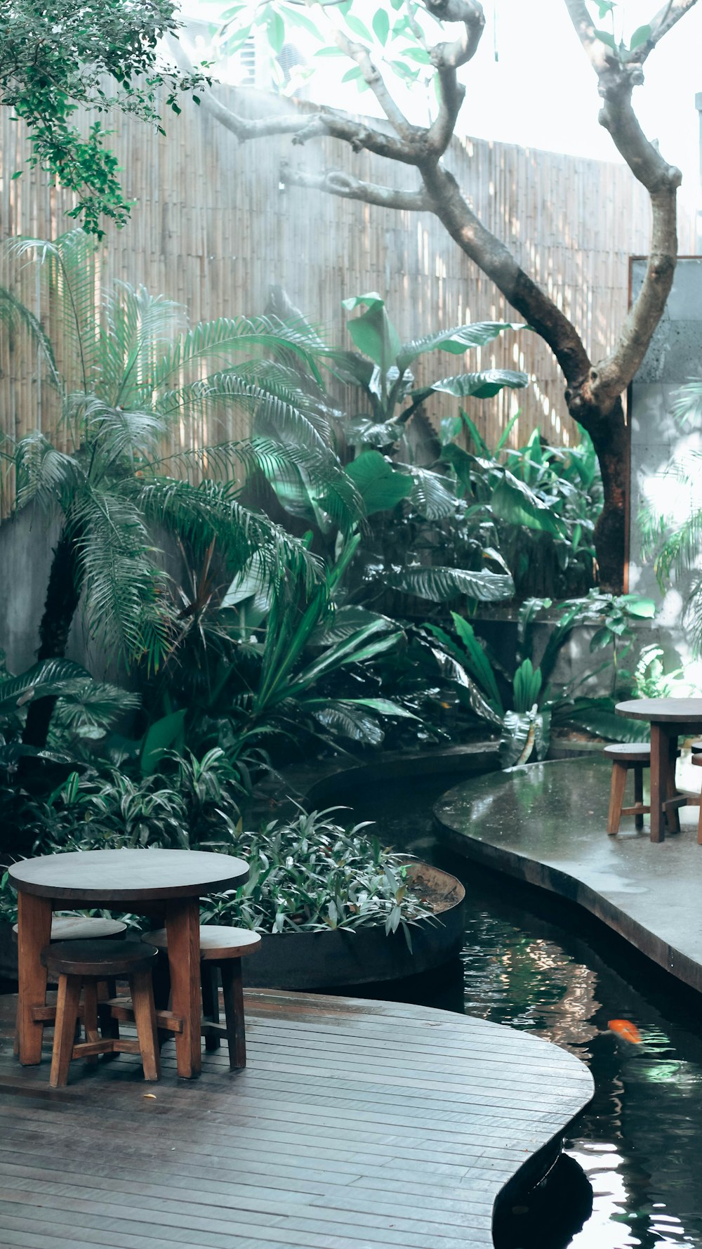 a wooden deck with a table and stools next to a pond