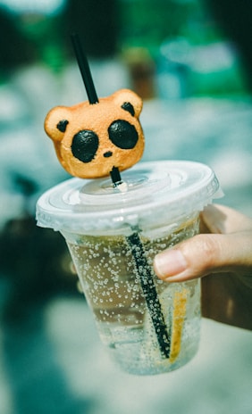 Colorful Italian soda in a kawaii cup with a panda illustration, surrounded by fresh fruit and ice.