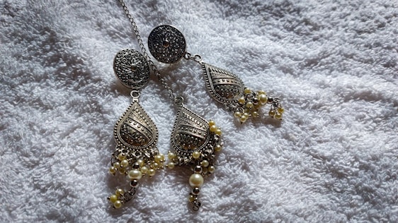 A close-up of elegant earrings displayed on a soft fabric background.