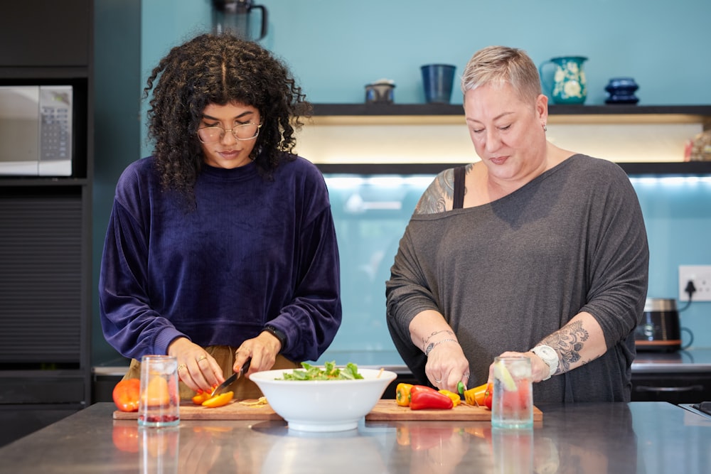 a couple of women standing in a kitchen preparing food