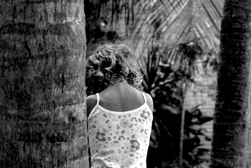 a woman standing in front of a palm tree