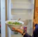 A smiling young woman enjoying a vibrant salad bowl in a bright, modern kitchen.