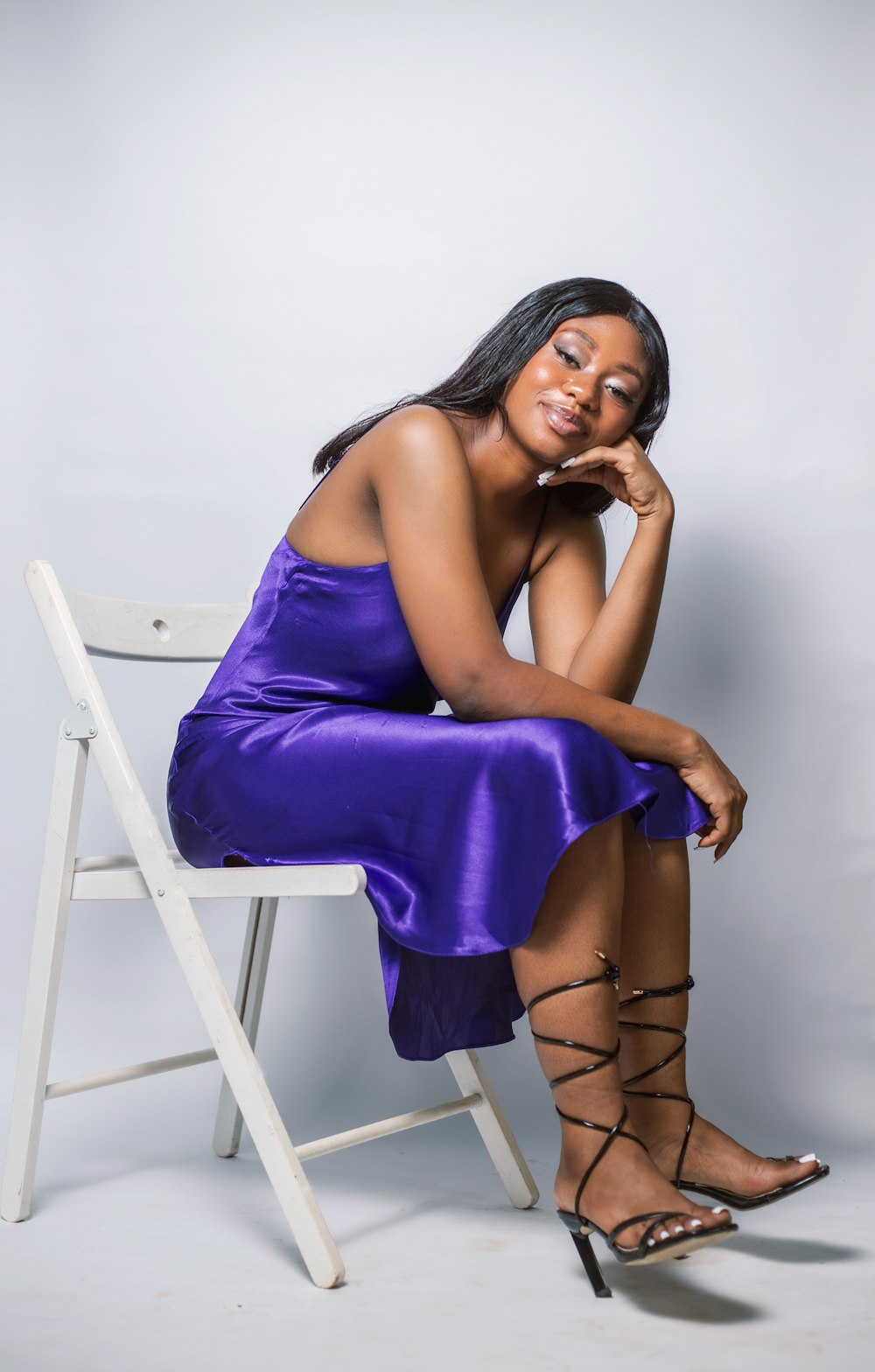 a woman in a purple dress sitting on a chair