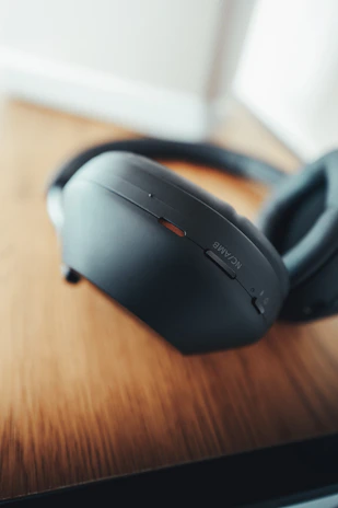 A pair of high-quality over-ear headphones resting on a wooden table.