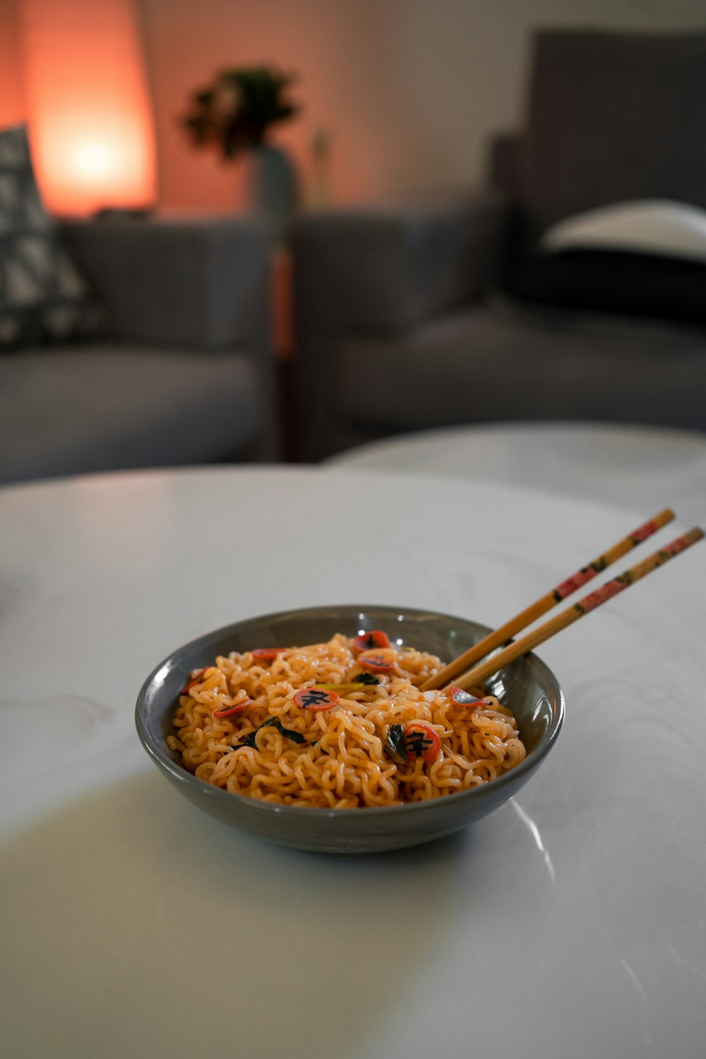 a bowl of noodles with chopsticks on a table