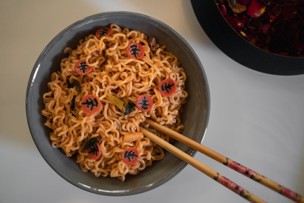 a bowl of noodles with chopsticks on a table