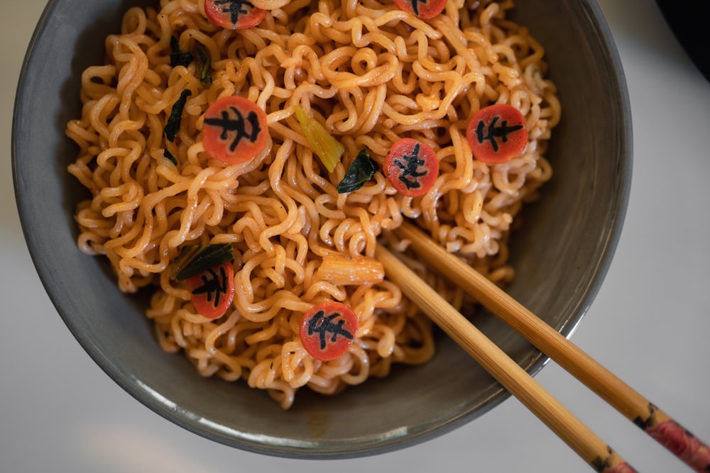 a bowl of noodles with chopsticks in it