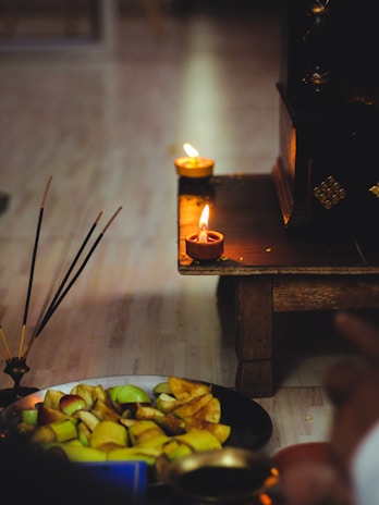 Softly lit scene showing a candle and a small offering bowl for adoçamento amoroso.