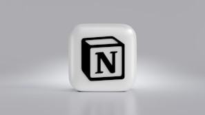 A cube-shaped object with a prominent black N logo in the center, set against a light gray background. The cube is three-dimensional with a smooth, white surface.