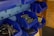 A collection of blue plastic bins mounted on a wall, containing various hardware items such as screws, nails, and hooks. The bins are organized, giving a tidy appearance, with some items packaged in plastic.