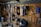 A well-organized workshop scene displays various power tools and hand tools neatly hung on a wooden wall. The tools include drills, screwdrivers, pliers, and wrenches, among others. The background is made of wooden planks, creating a rustic ambiance.