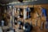 A well-organized workshop scene displays various power tools and hand tools neatly hung on a wooden wall. The tools include drills, screwdrivers, pliers, and wrenches, among others. The background is made of wooden planks, creating a rustic ambiance.