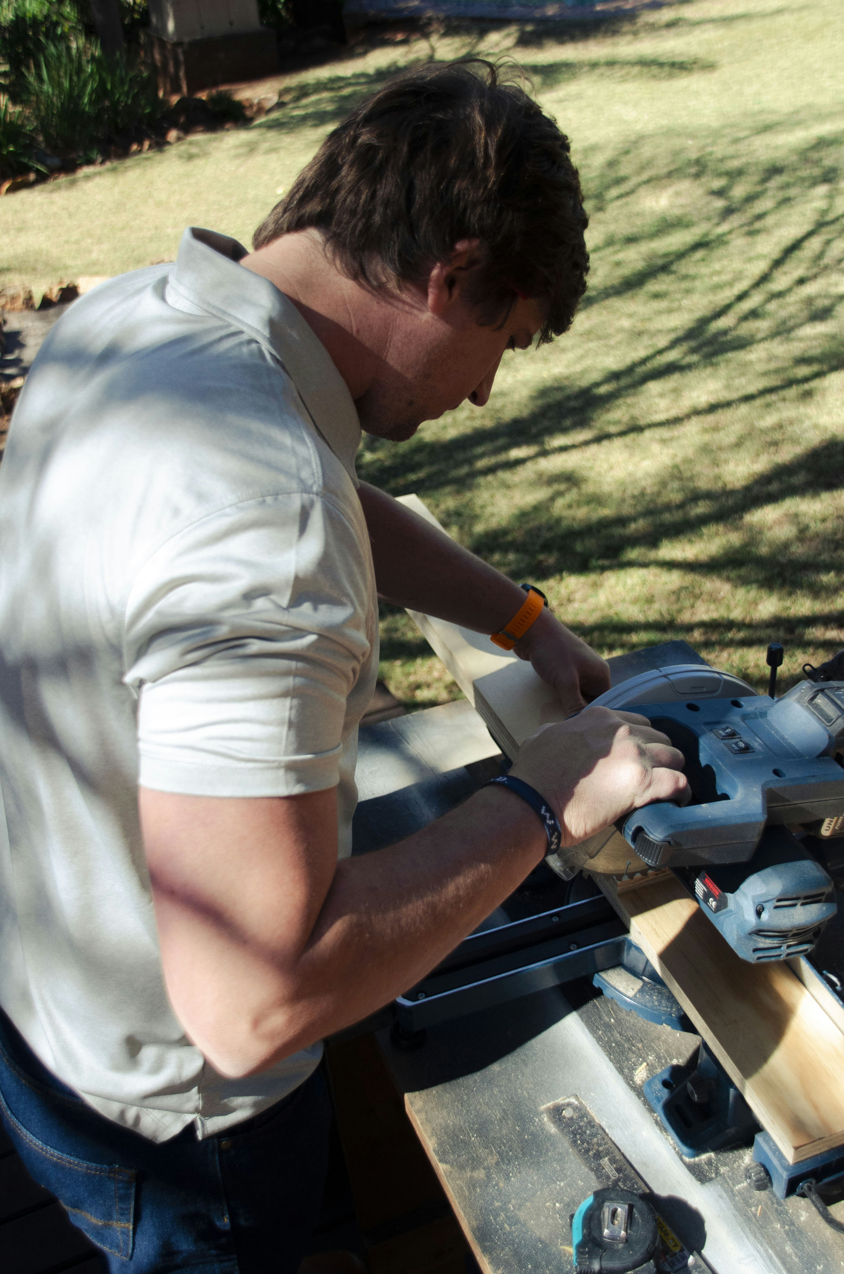 a man sanding a piece of wood with a circular saw