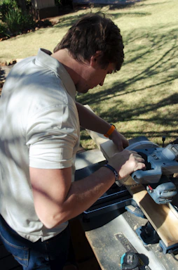 a man sanding a piece of wood with a circular saw