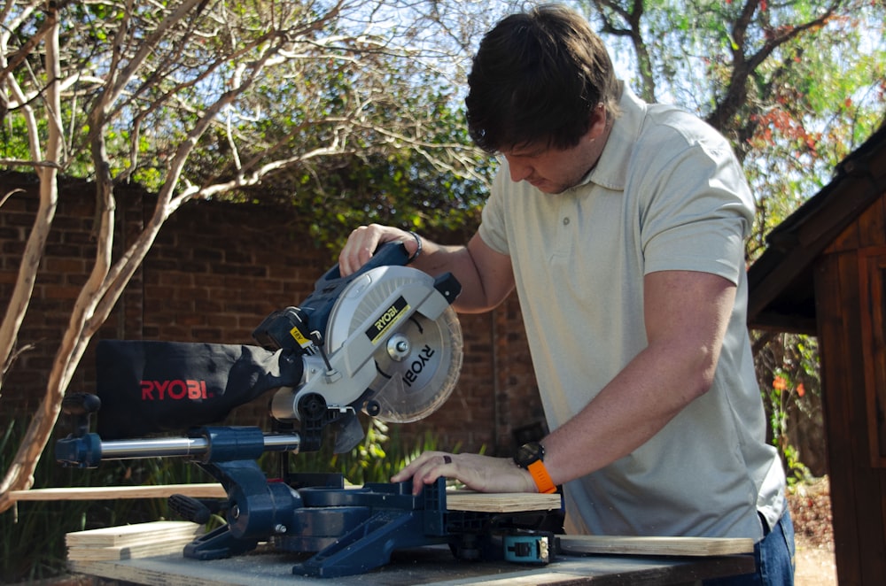 a man using a circular saw to cut a piece of wood