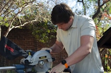 a man using a circular saw to cut a piece of wood